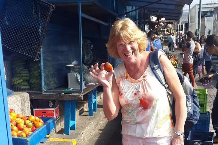 Woman enjoying fresh produce at a vibrant market during San Jose's Bites and Sights Walking Food Tour.