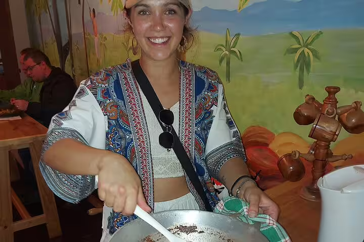 Smiling woman stirring traditional dish during San Jose food tour in a colorful market setting.