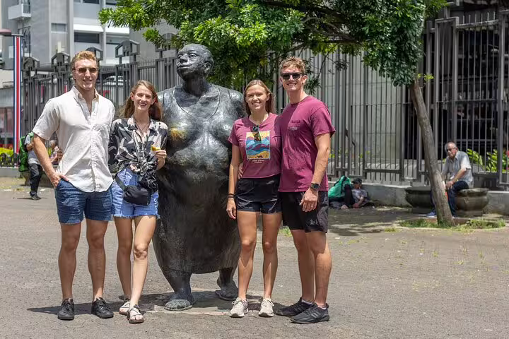 Tourists pose with a statue in San Jose's vibrant streets, part of the Bites and Sights Walking Food Tour experience.
