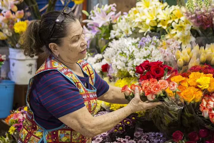 Florist arranging vibrant bouquets of roses and lilies at a San Jose market on the Bites and Sights Walking Food Tour.