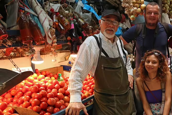 Local vendor and tourists explore vibrant produce at a San Jose market on the Bites and Sights Walking Food Tour.