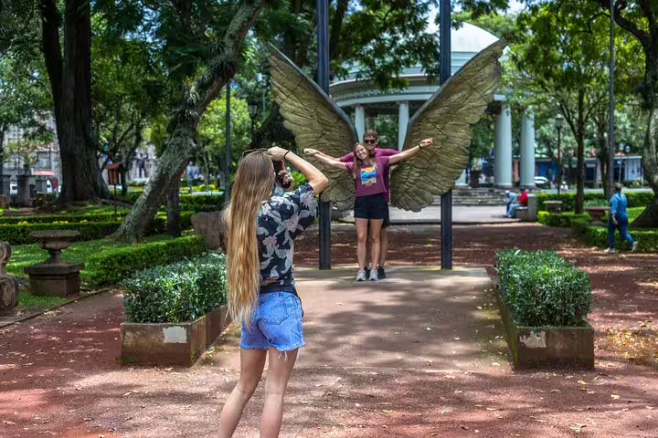Visitors posing with angel wings sculpture in a San Jose park, capturing the essence of a vibrant city tour.