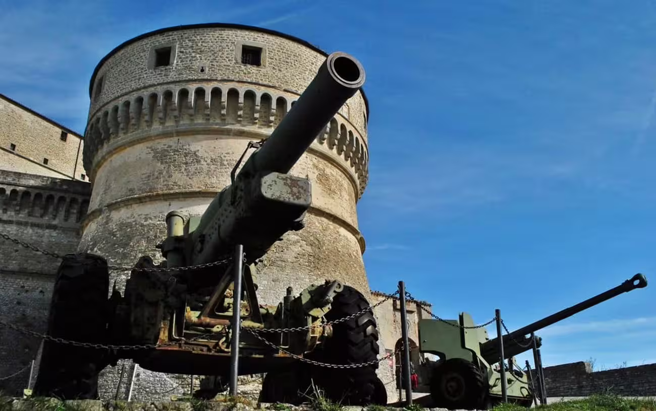 Historical cannons displayed at San Leo Fortress, emphasizing its medieval military significance under a clear blue sky.