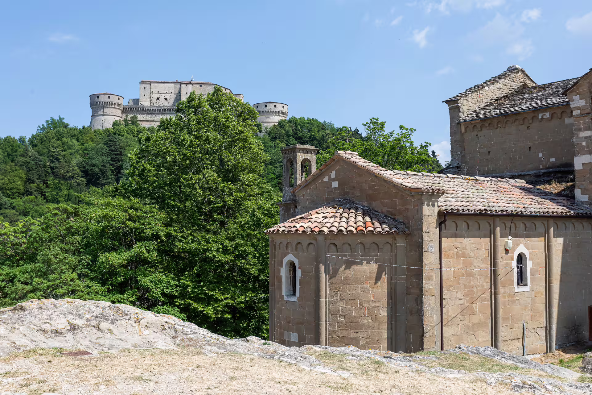 View of San Leo Fortress perched on a lush hilltop, showcasing historical architecture surrounded by vibrant greenery.