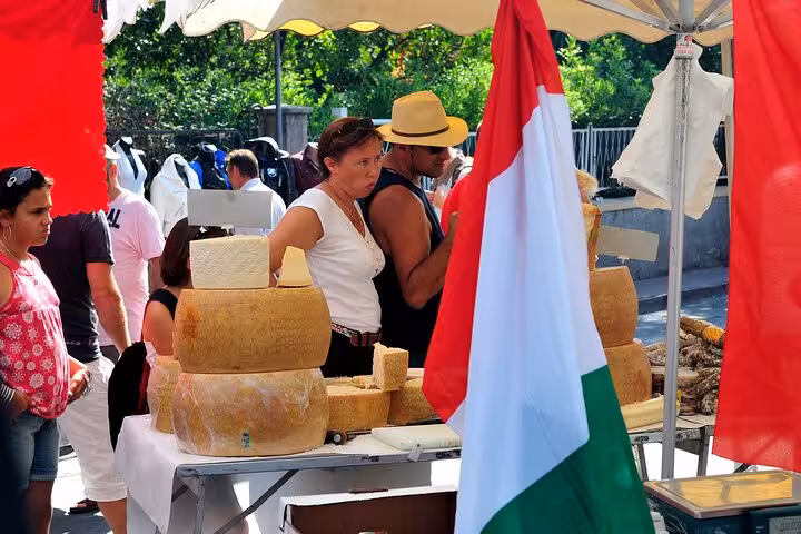 Vendor selling large wheels of aged cheese at San Remo market with Italian flag display