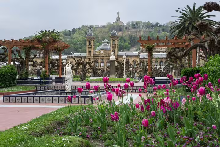 San Sebastian city hall and gardens with pink tulips, statues, and pergolas in spring