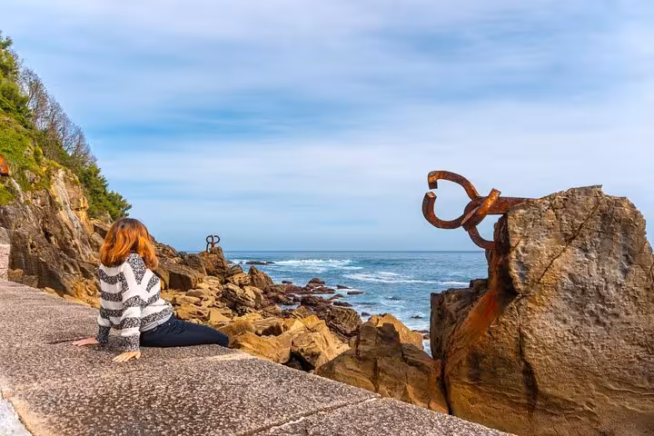 Traveler admiring San Sebastian's coastal sculpture, blending art and nature on a scenic city walk with local guide.