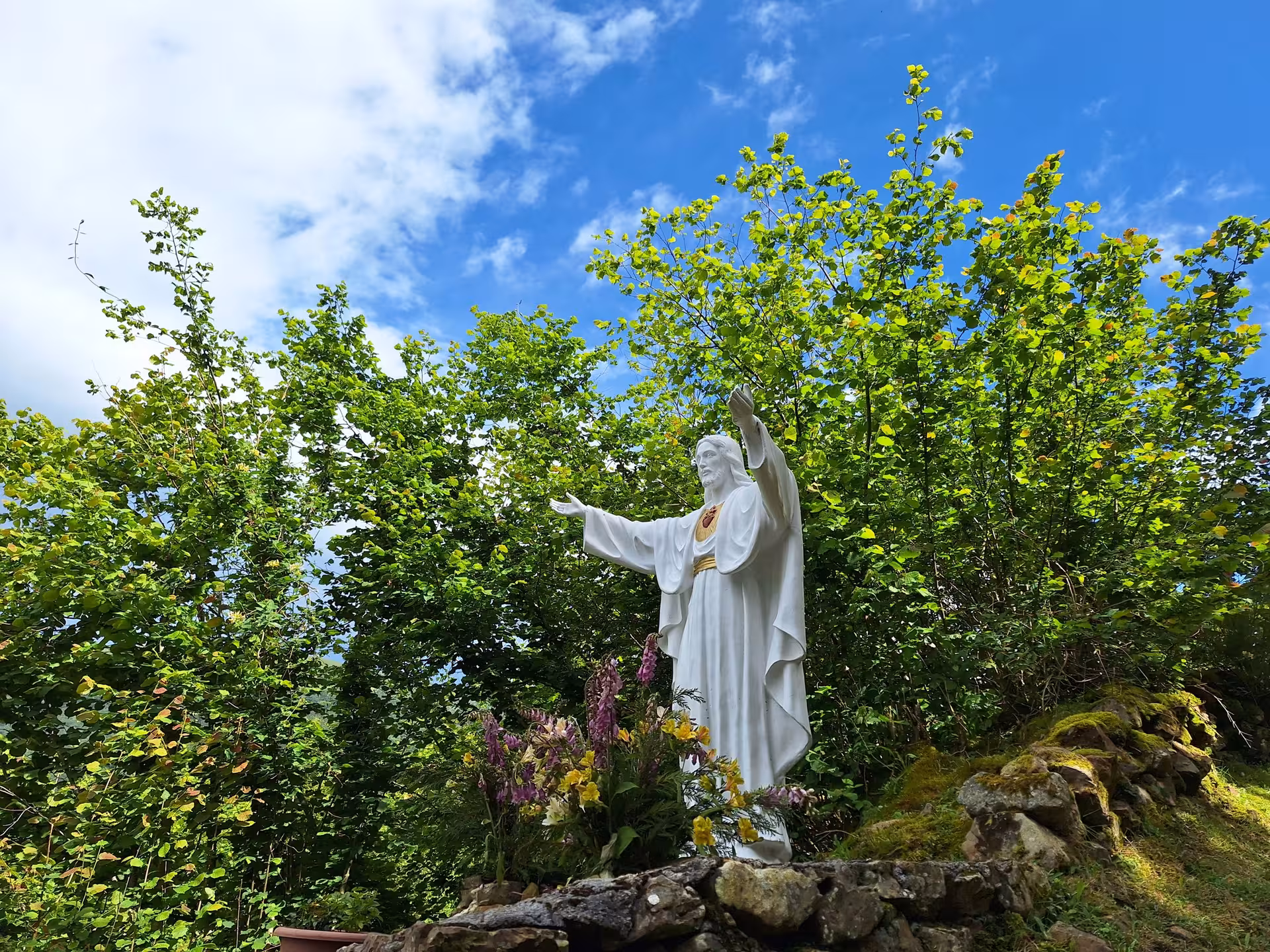 Serene statue surrounded by lush greenery in San Sebastian De Garabandal, ideal for cultural exploration.