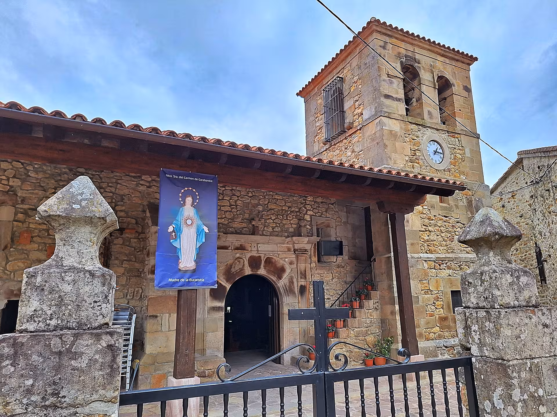 Explore the historic stone church in San Sebastian De Garabandal, featuring a clock tower and religious iconography.