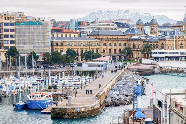 San Sebastian waterfront marina with historic buildings and snow-capped mountains in the background