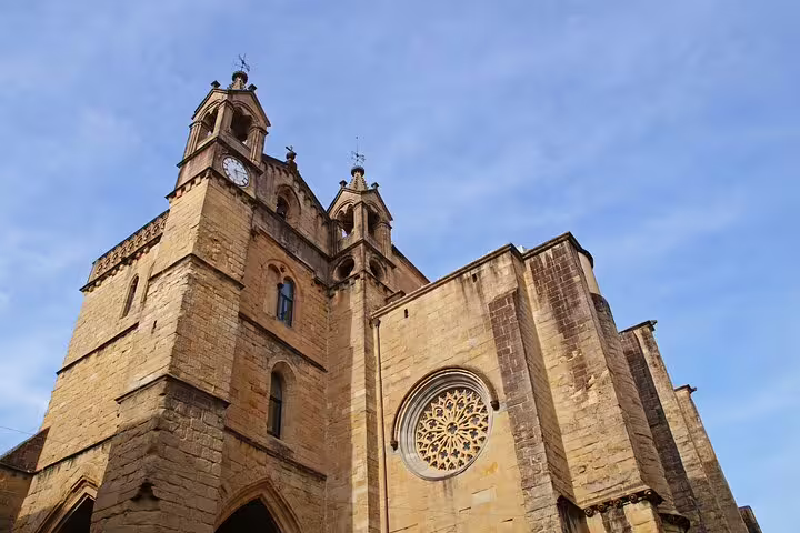 Gothic stone church facade with rose window and clock tower in San Sebastian Old Town