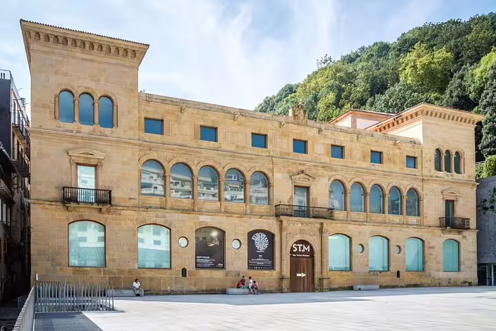 Historic sandstone building of San Sebastian Old Town with arched windows and plaza in foreground