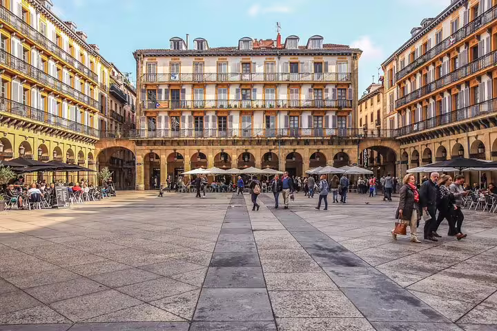 Plaza de la Constitución in San Sebastian Old Town with historic arcaded buildings and tourists walking across stone square