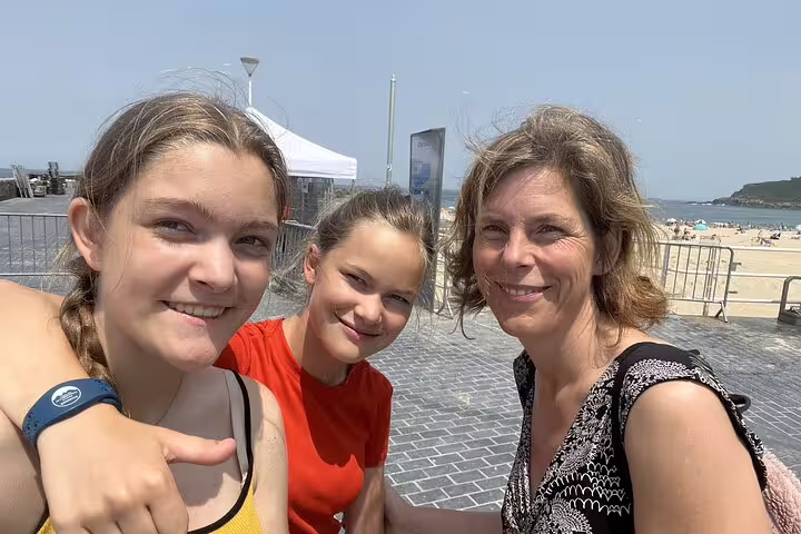 Three smiling women taking a selfie near San Sebastian beach on a sunny day