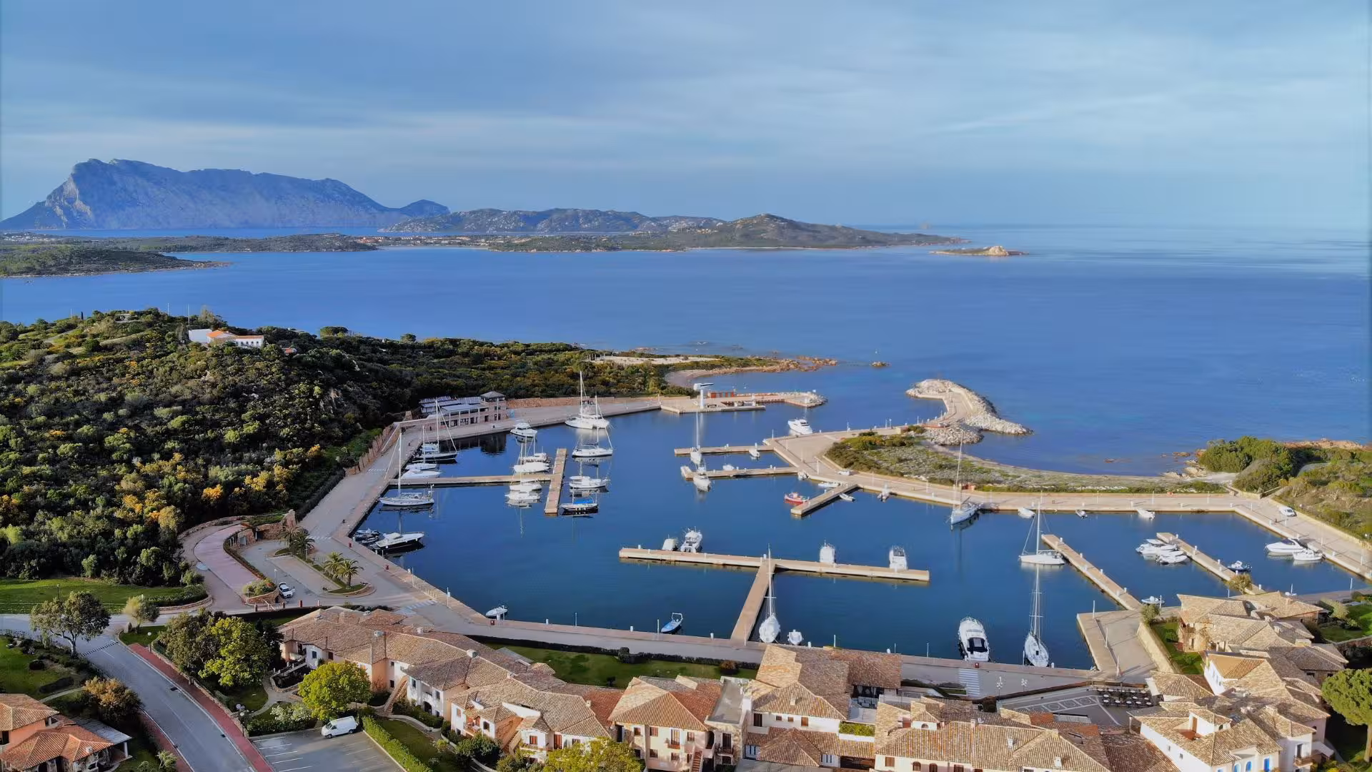 Panoramic view of San Teodoro marina with yachts and Tavolara Island in the background.