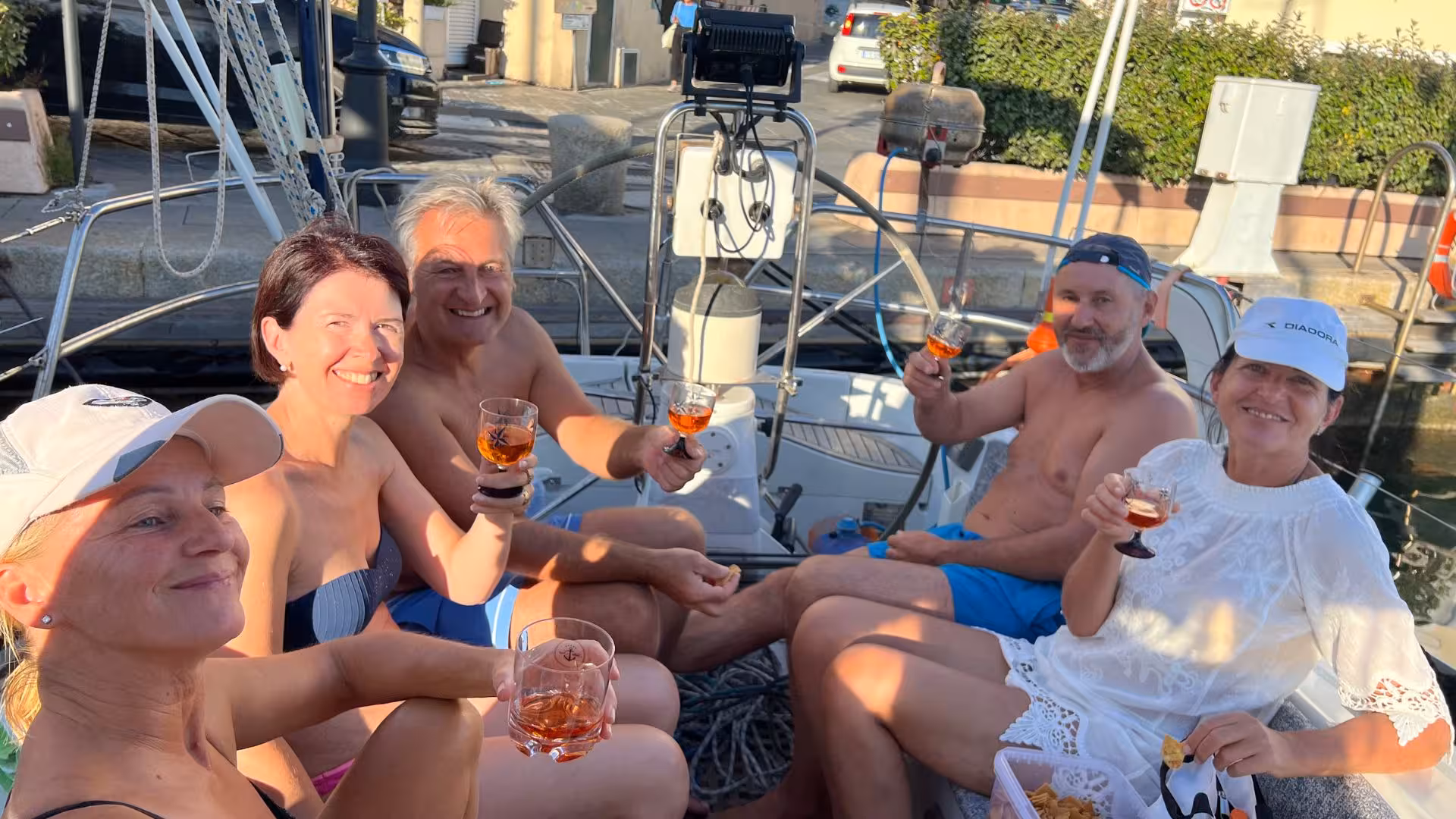 Group enjoying drinks on a San Teodoro sailing boat tour, capturing joyful moments and scenic marina views.