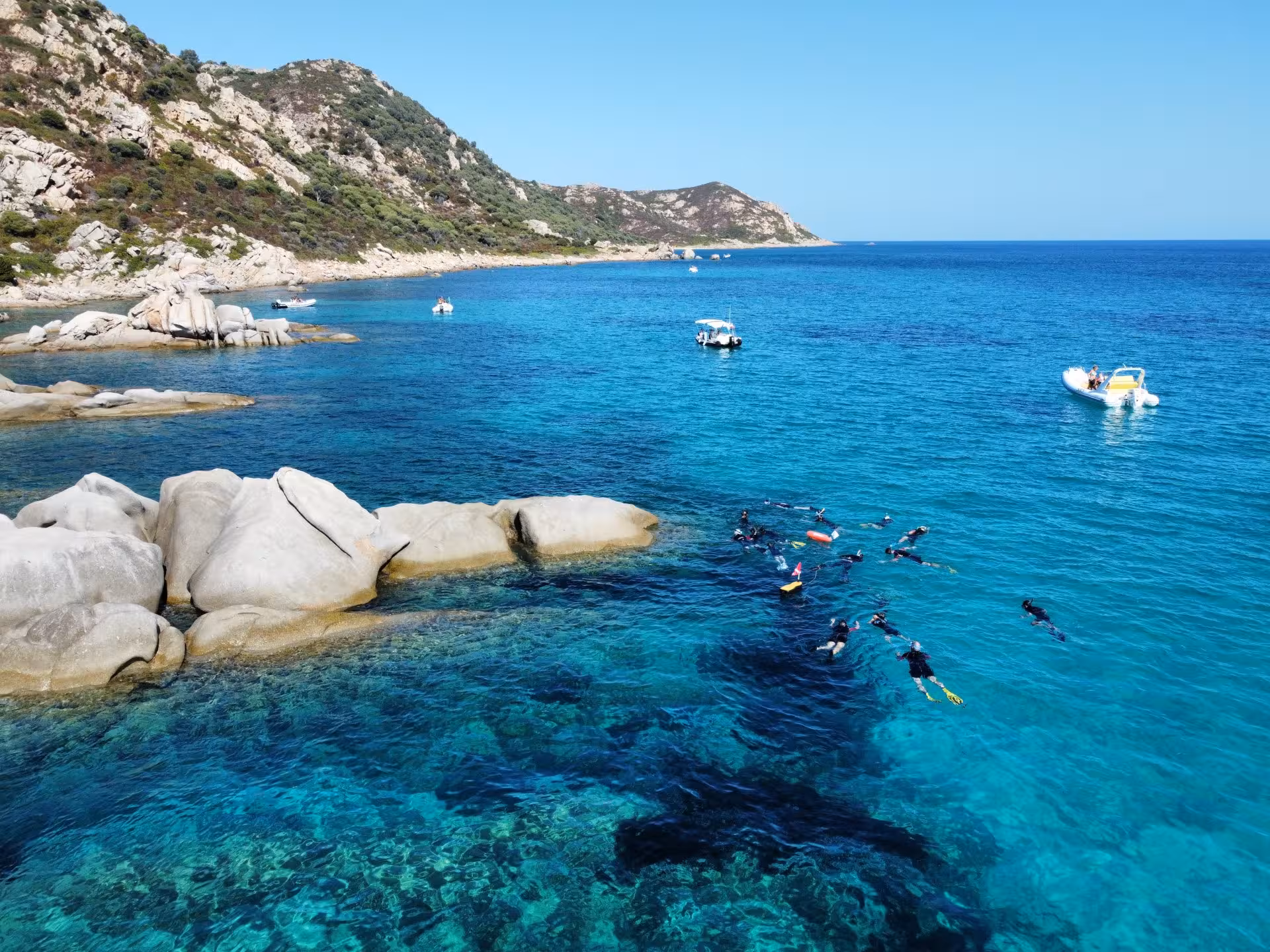 Snorkelers explore the turquoise waters near Molara's rocky coastline, a highlight of San Teodoro snorkeling tours.