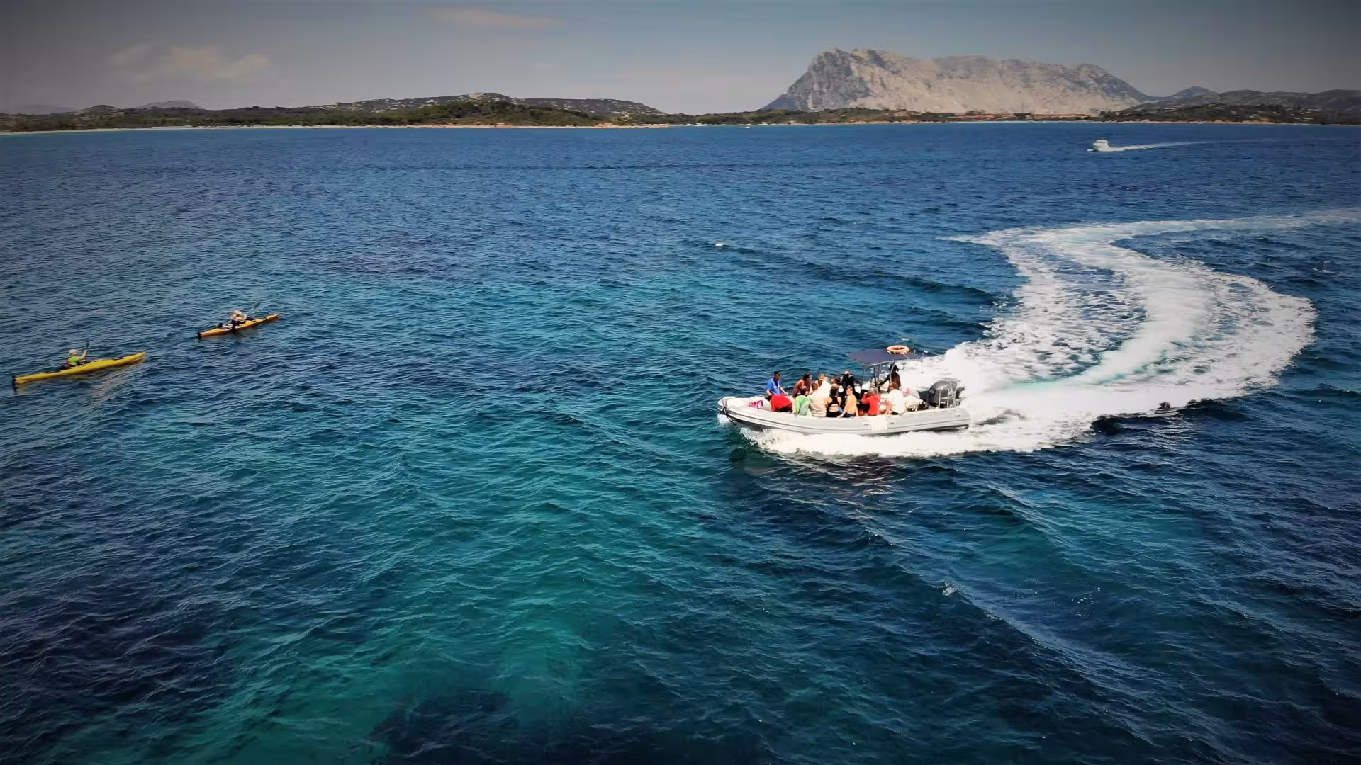Tourists enjoy a speedboat ride in turquoise waters near San Teodoro, ideal for snorkeling and exploration.