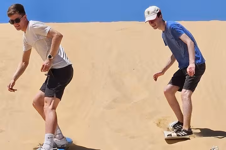 Sandboarding down Fayoum desert dunes near Magic Lake on a Cairo day trip adventure tour in Egypt