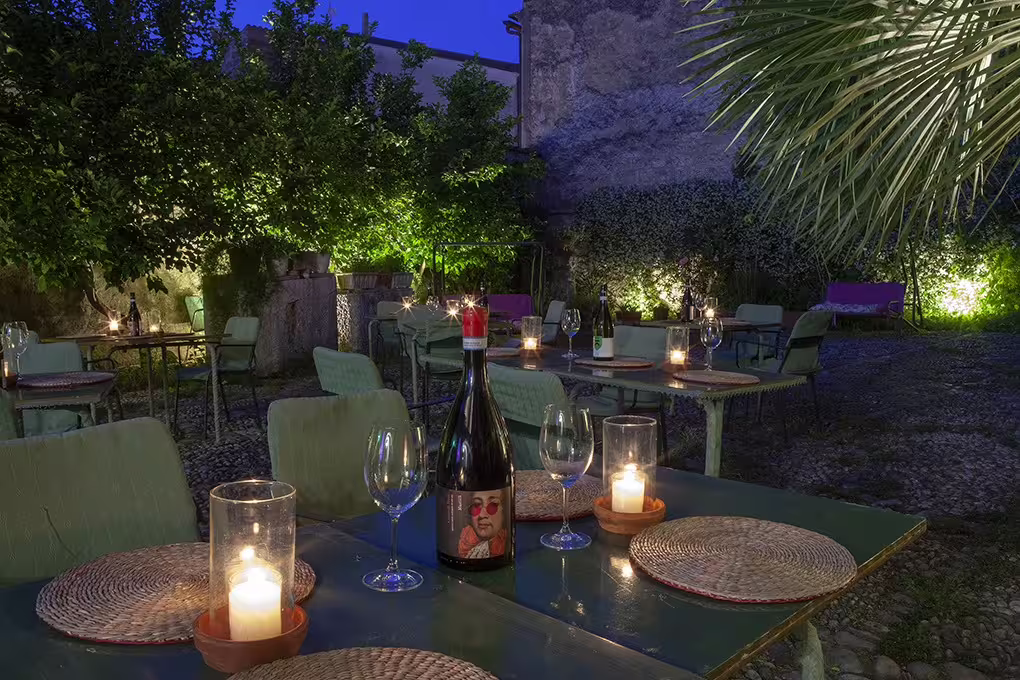 Romantic candlelit wine tasting setup in a lush garden courtyard in Sant'Agata de' Goti at blue hour