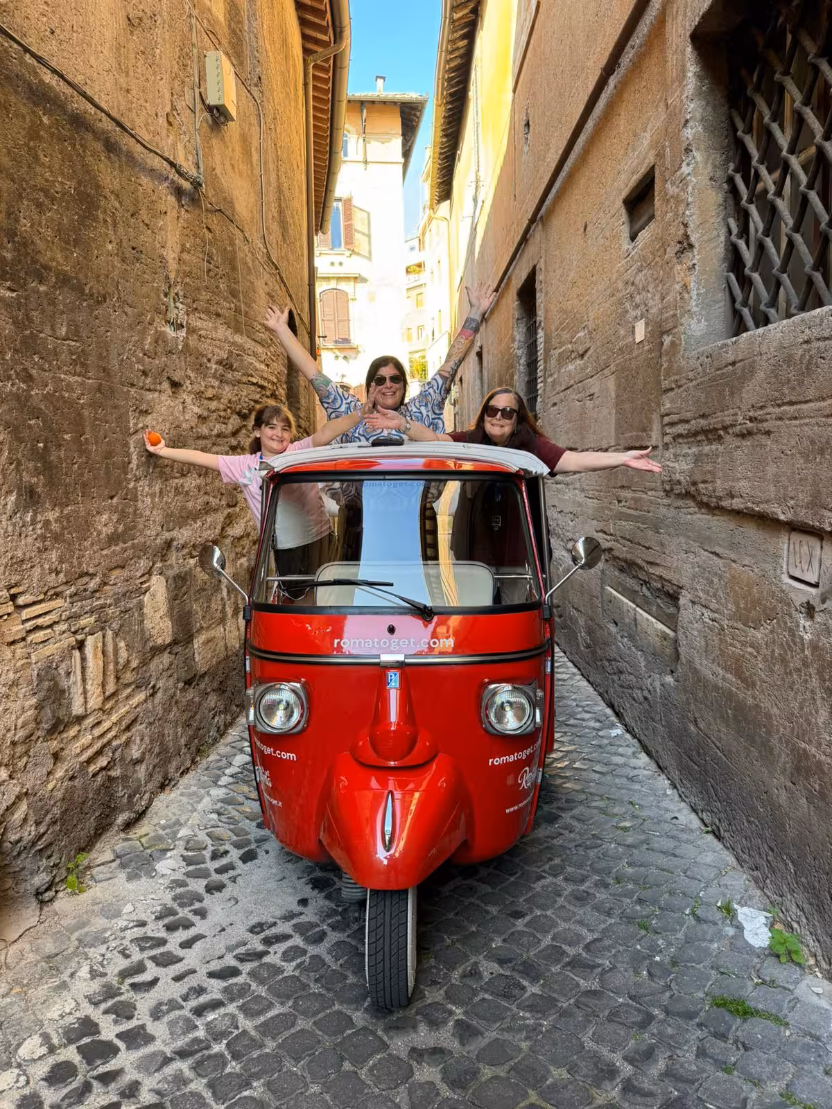 Excited tourists in a narrow alley exploring Rome's charm on a Sant'Angelo Castle Combo Tour tuk-tuk ride.