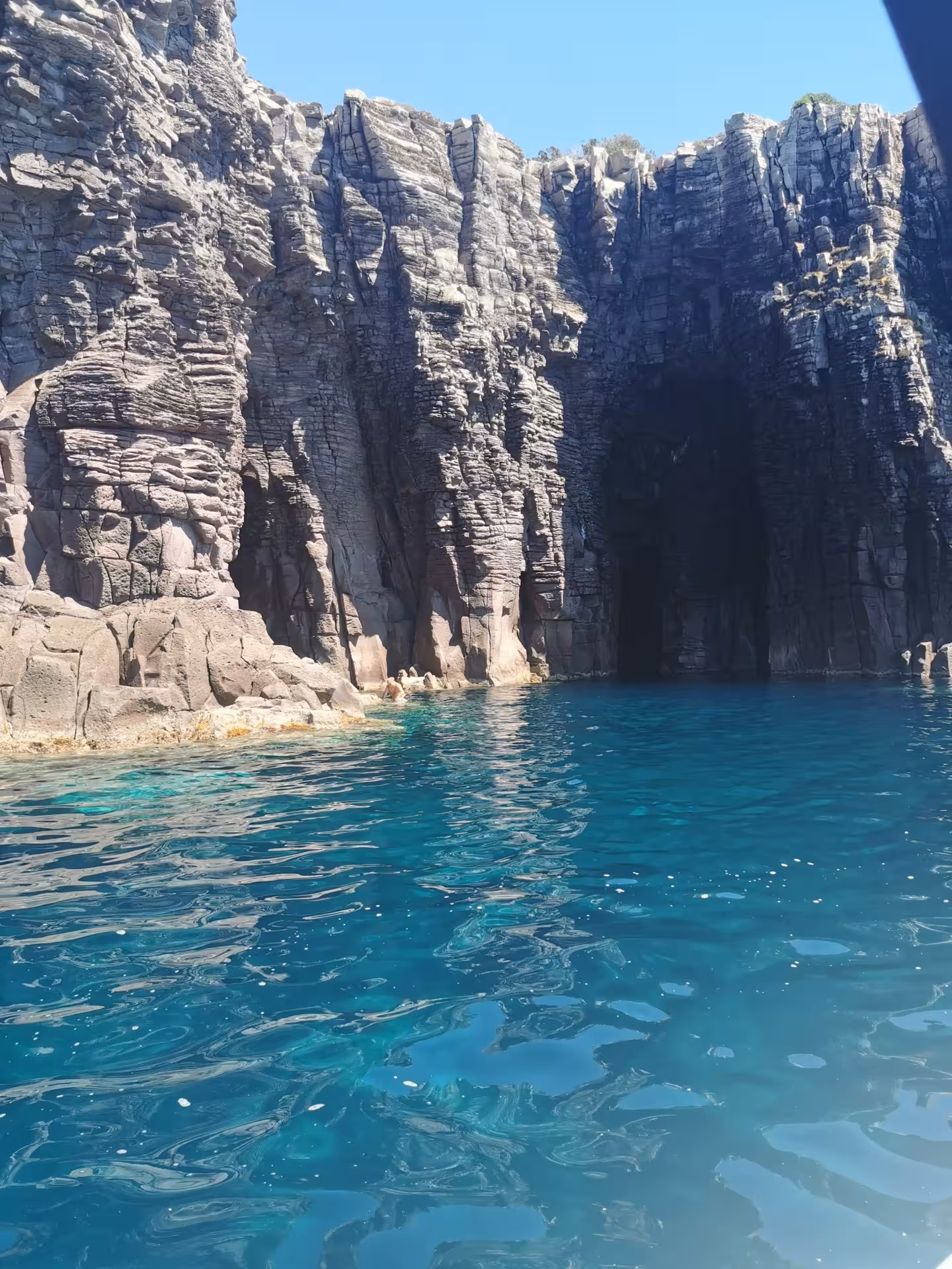 Explore the towering coastal cliffs on a Sant'Antioco RIB tour with crystal-clear blue waters and rugged rock formations.