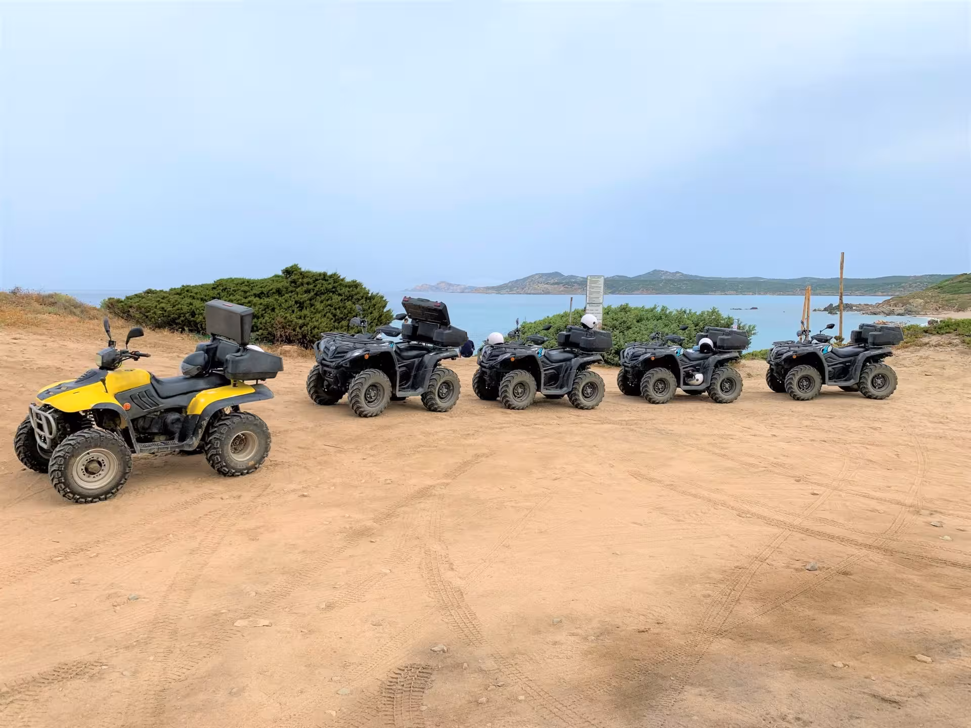 Line of ATVs on a sandy trail with ocean view, perfect for Santa Teresa di Gallura's 3-hour ATV adventure.
