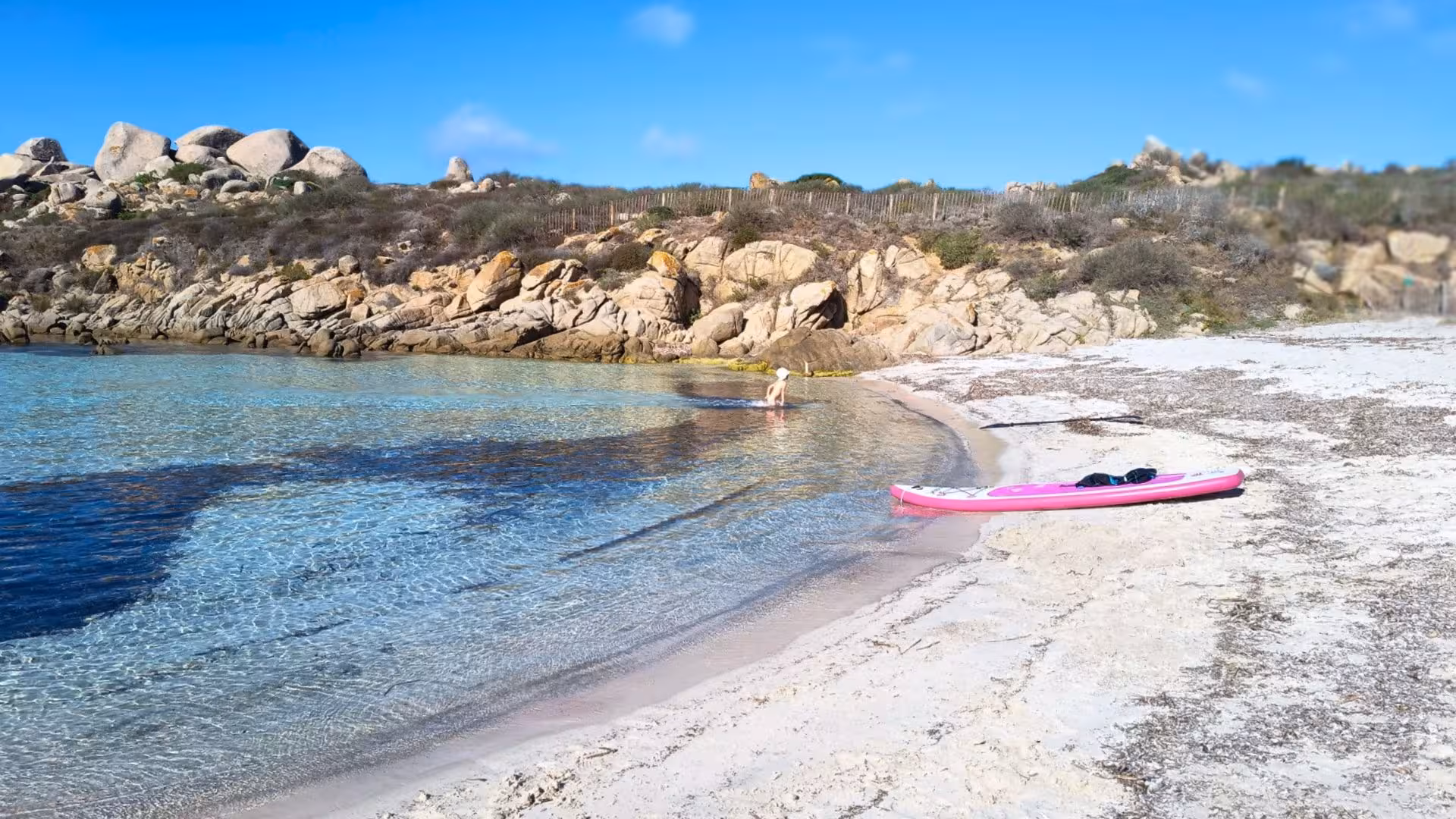 Serene sandy beach with a kayak and crystal waters, ideal for a Santa Teresa di Gallura to southern Corsica sailing tour.