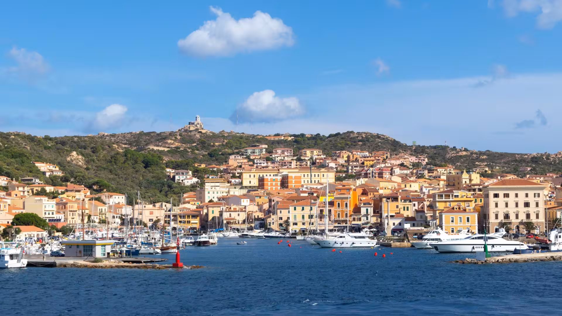 The picturesque harbor of Santa Teresa Gallura with colorful buildings and anchored boats in the La Maddalena Archipelago.