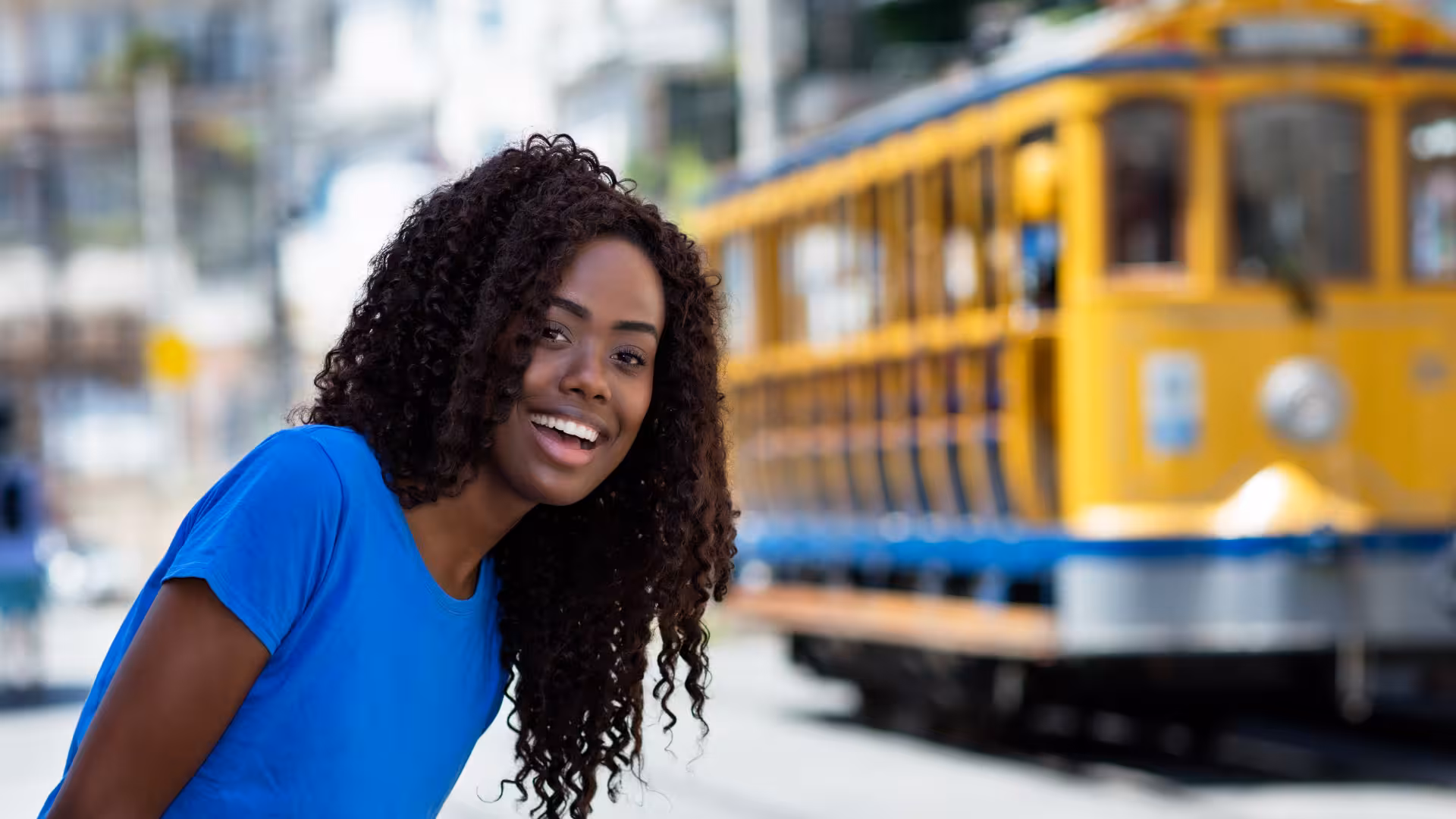 Smiling visitor enjoying the vibrant atmosphere of Santa Teresa with the iconic yellow tram in the background.
