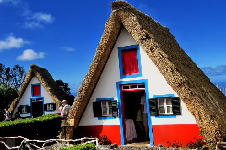 Traditional Santana houses with thatched roofs in Northeast Madeira, showcasing cultural charm on a full-day guided tour.