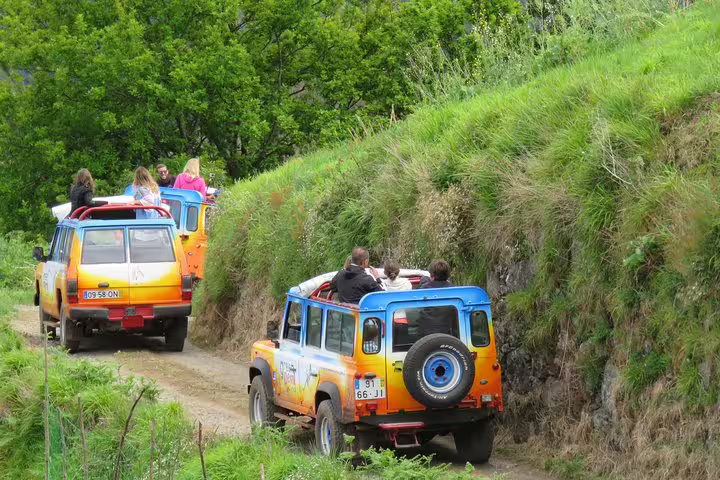 Off-road 4x4 vehicles navigate lush green trails on the Santana & Peaks tour, offering an adventurous Madeira island excursion.