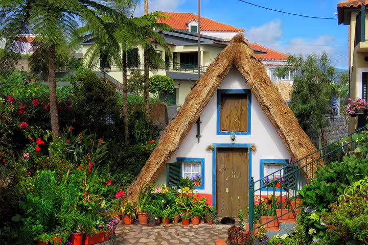 Charming traditional Santana house with thatched roof, surrounded by vibrant gardens on the Northeast 4x4 tour excursion.