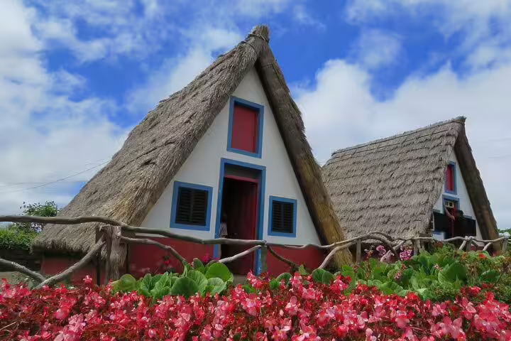 Traditional Santana A-frame houses with thatched roofs and vibrant flowers, featured in the Northeast 4x4 tour excursion.