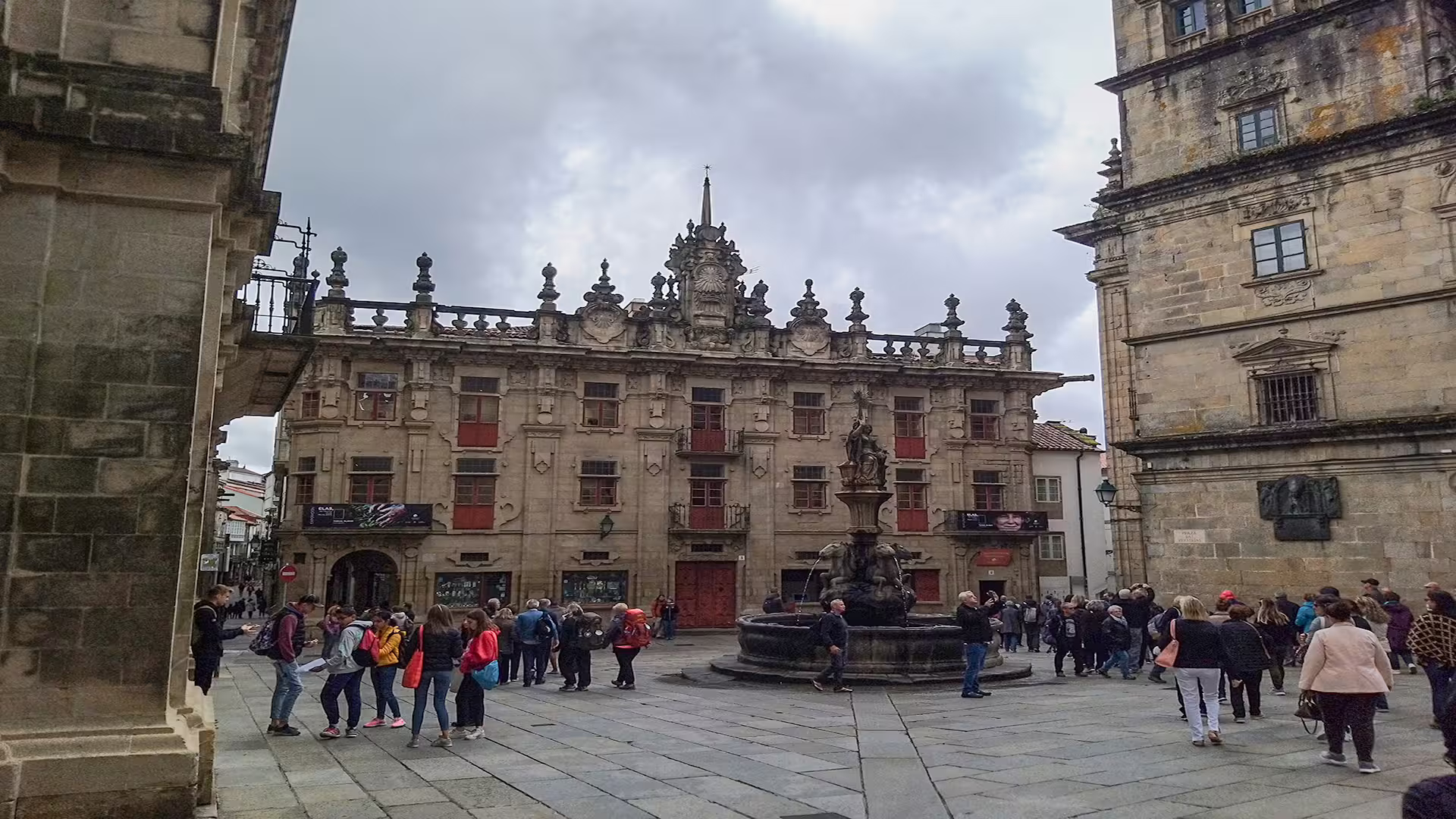 Tourists gather near the historic fountain and architecture in Santiago de Compostela, highlighting the vibrant atmosphere of the cathedral tour.