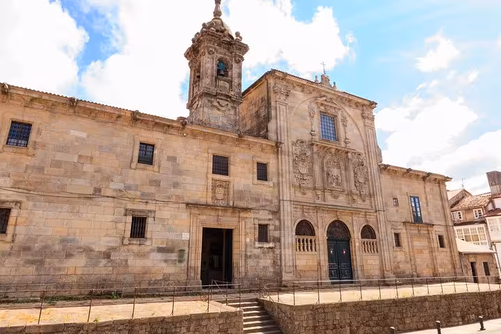 Historic stone facade of a church in Santiago de Compostela, showcasing detailed architecture on a sunny day.