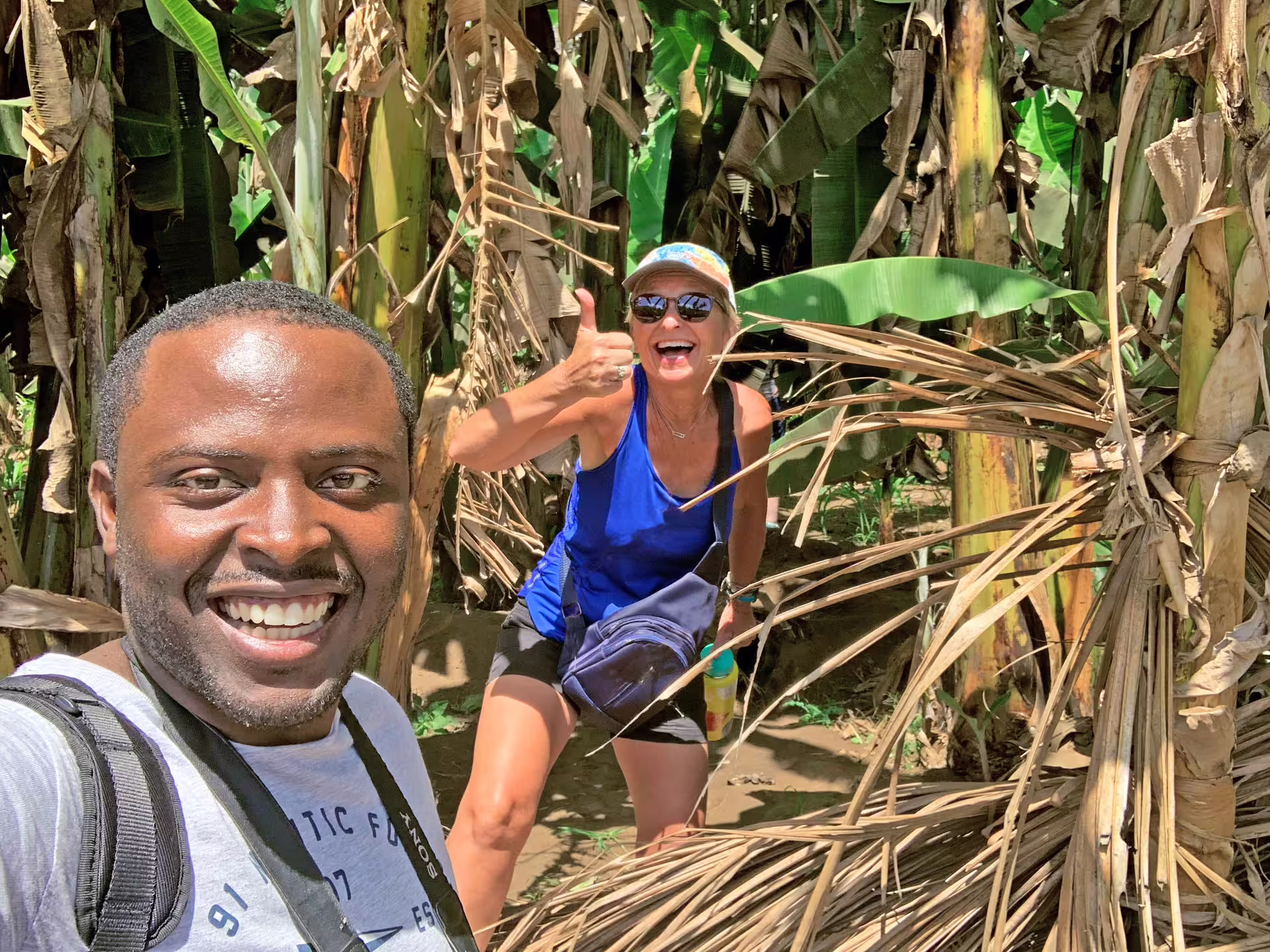 Smiling visitors enjoying a close-up experience among banana trees on Santiago Island plantation tour.