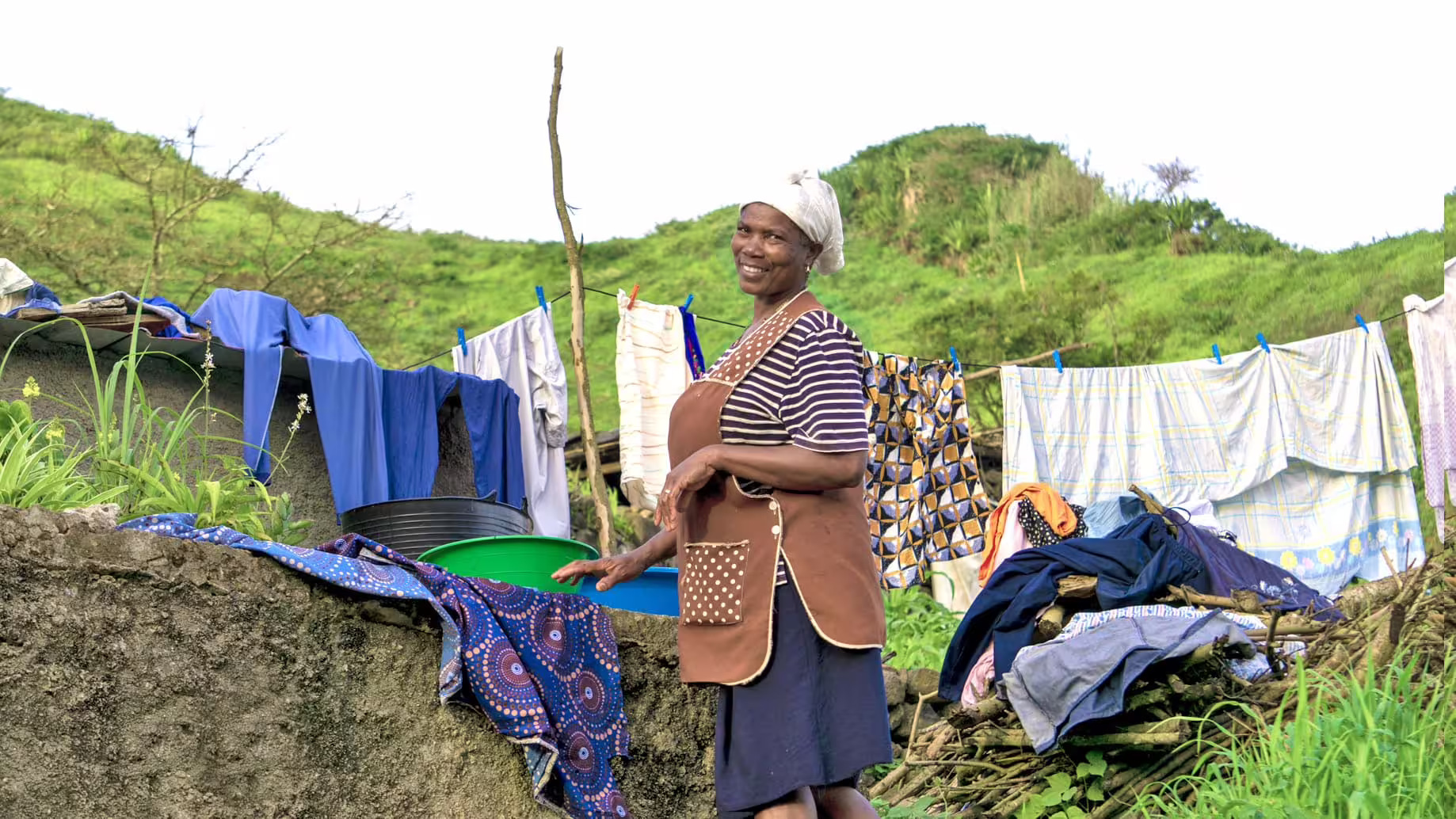 Local woman cheerfully doing laundry outdoors, depicting daily life and community interaction on Santiago Island.