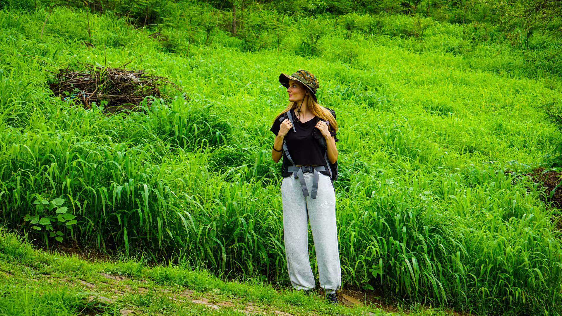 A woman in casual attire hikes through the lush greenery of Santiago Island's Longueira trail, enjoying the natural beauty.