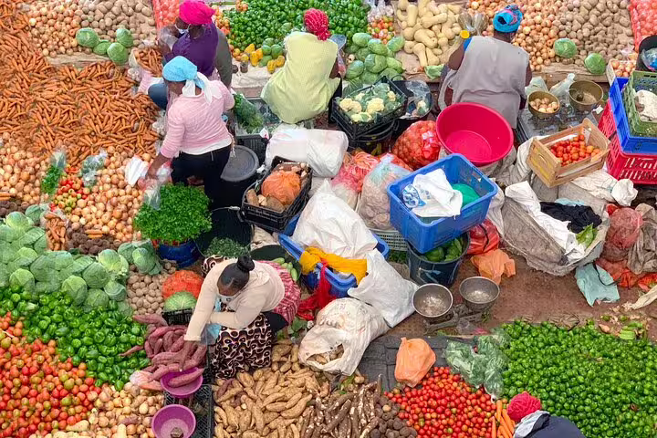 Aerial view of a bustling Santiago Island market with diverse vegetables and locals engaging in trade.