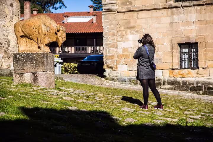 Tourist photographing bison statue in Santillana del Mar, capturing cultural heritage on a Santander tour.