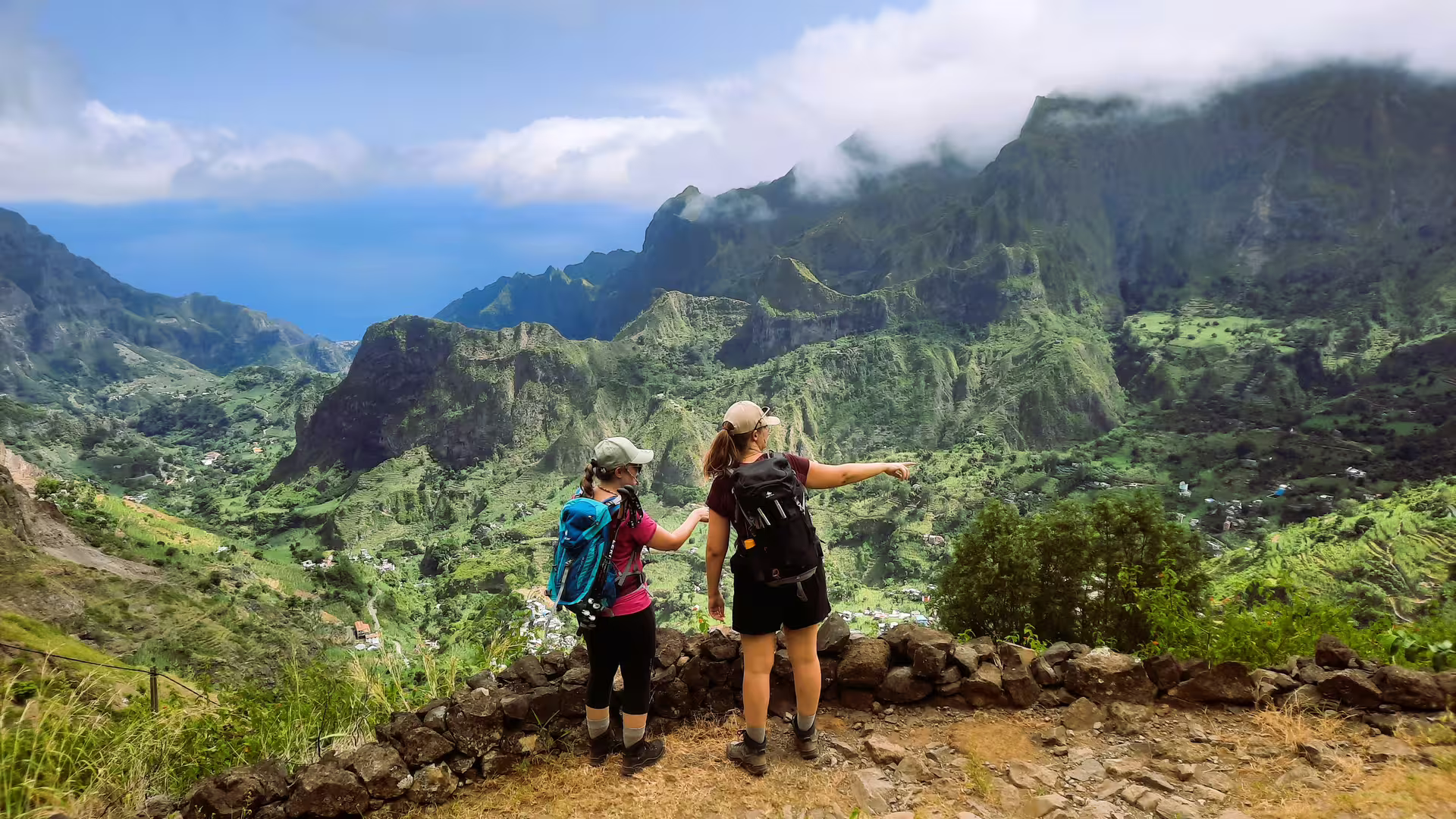 Two hikers admire the breathtaking view of lush valleys on Santo Antão's Cova de Paúl volcano trek.