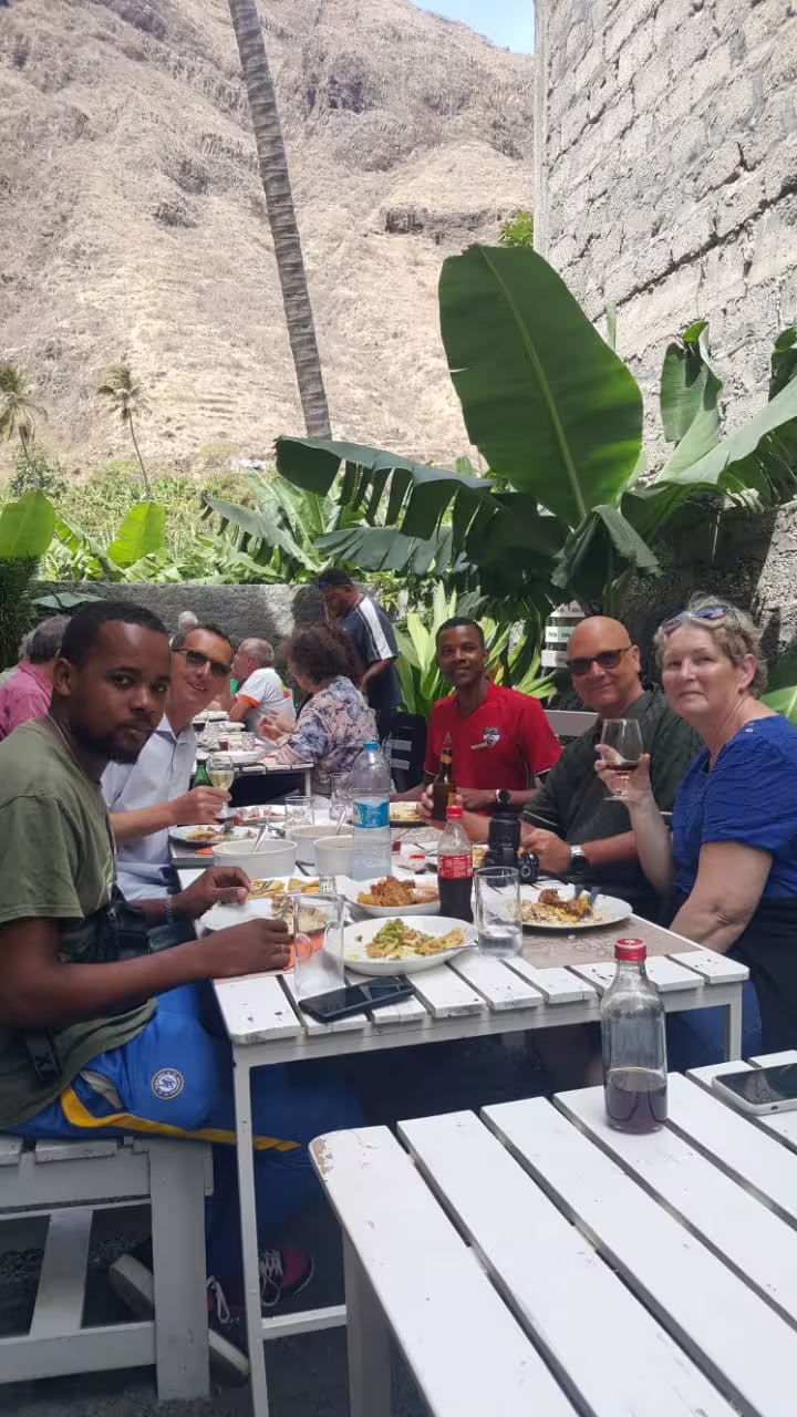 Group enjoying local cuisine outdoors in lush Santo Antão during an 11-hour São Vicente day trip tour by car.