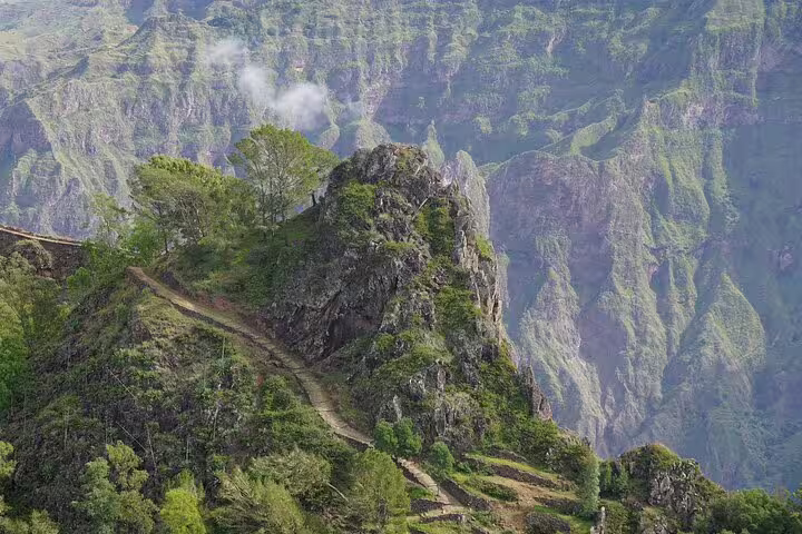 A scenic trail winding up a lush, rocky hill in Santo Antão, ideal for hiking on the Secret Trails Discovery Tour.