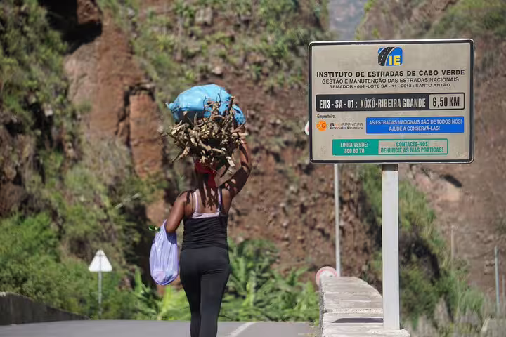 Local woman carrying supplies along a scenic Santo Antão trail, showcasing traditional life in Cape Verde's lush landscapes.