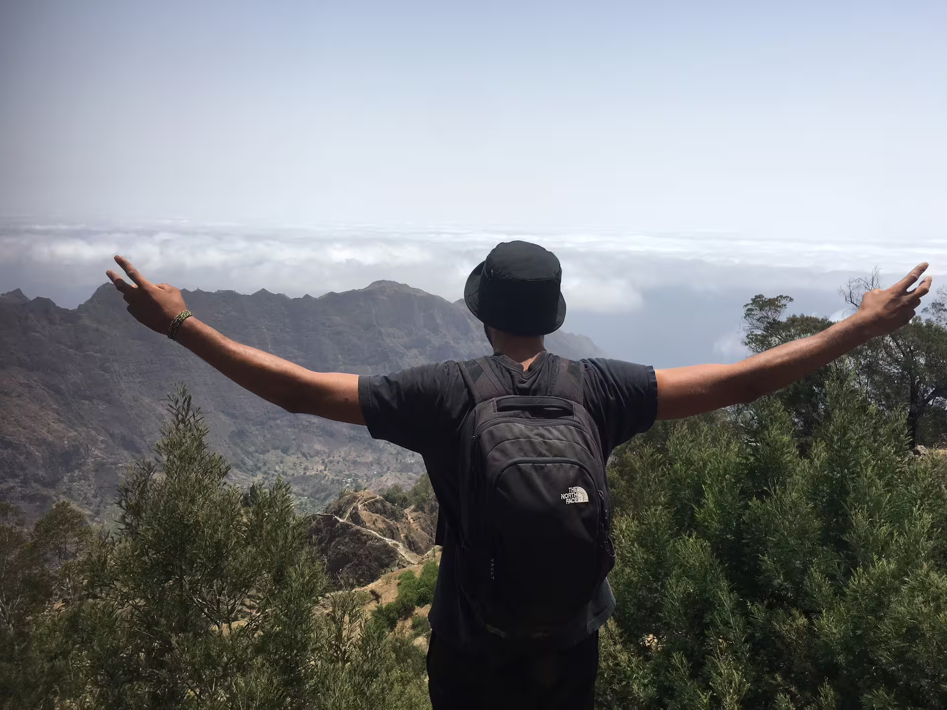 Traveler enjoying breathtaking mountain views on a day trip from São Vicente to Santo Antão, embracing nature's beauty.