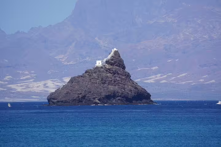Rocky islet with a small white structure surrounded by blue waters, a unique landmark on Santo Antão tours.