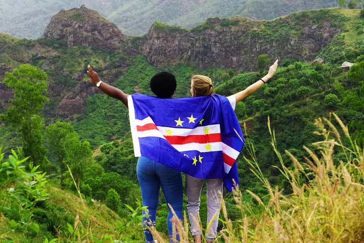 Two travelers with a Cape Verde flag embrace the stunning mountain views of Santo Antão, celebrating adventure and culture.