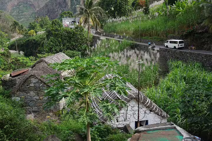 Scenic view of traditional thatched-roof stone houses in a lush valley of Santo Antão, perfect for eco-friendly tours.