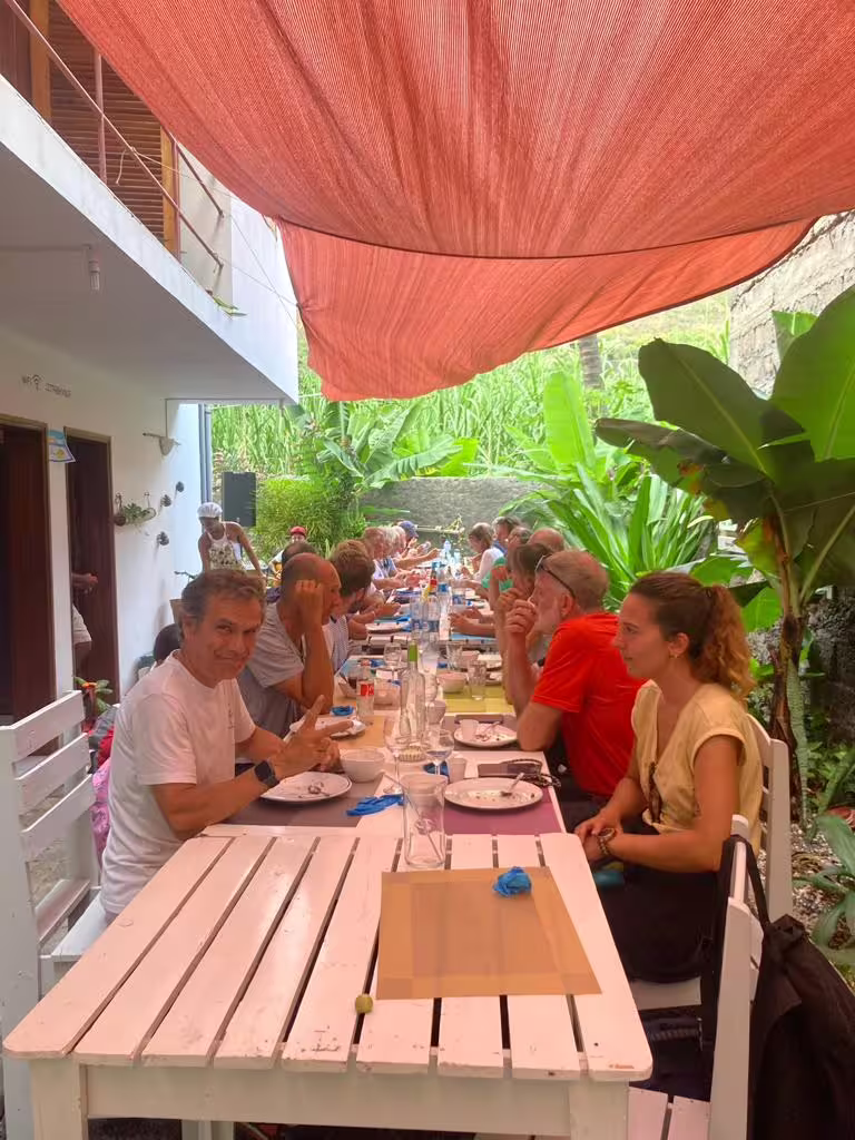 Travelers enjoying a communal meal under a canopy amidst lush greenery during the Santo Antão Valley of Paul trek.